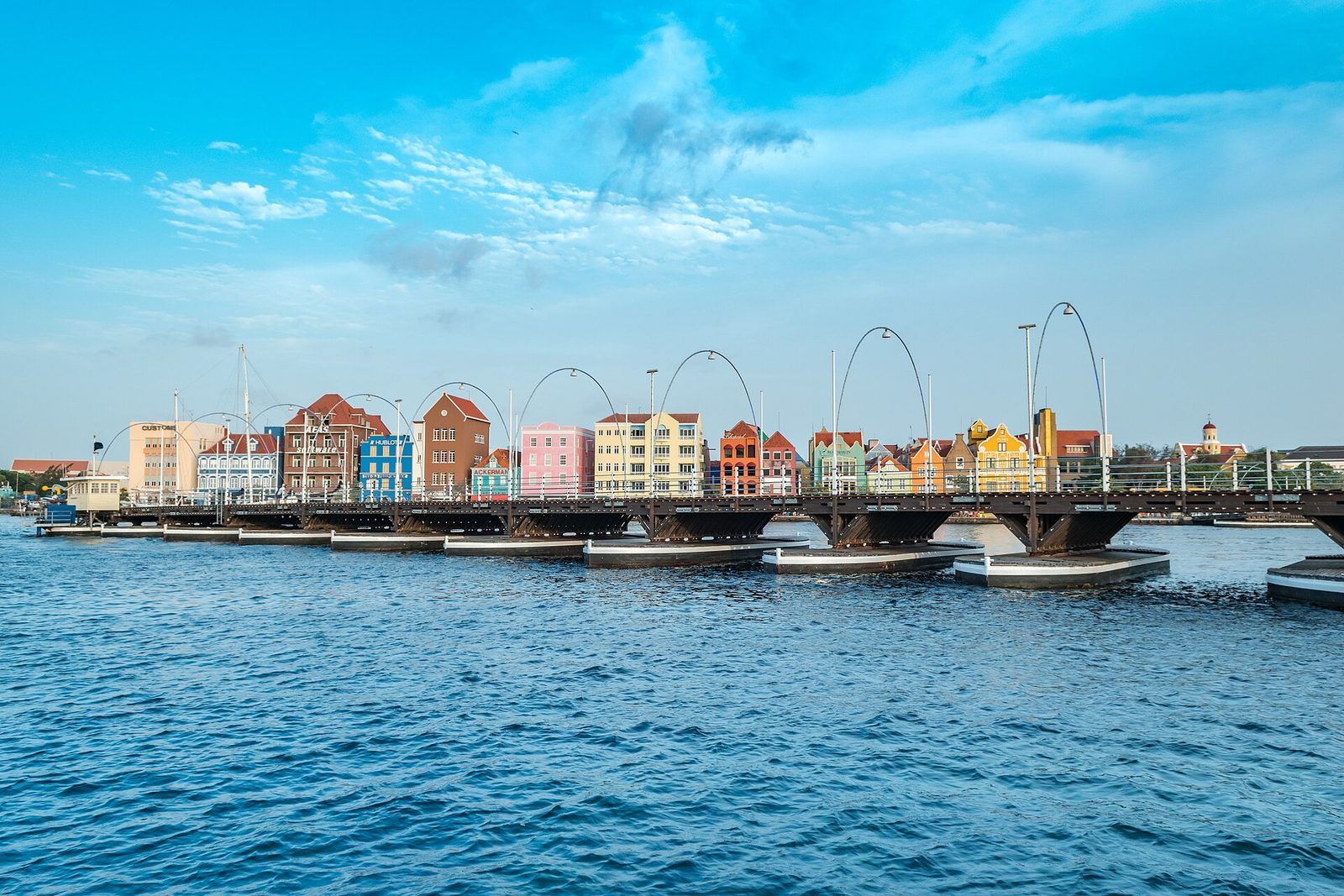 The Queen Emma Bridge on its pontoons, with the coloured facades of the Handelskade behind it